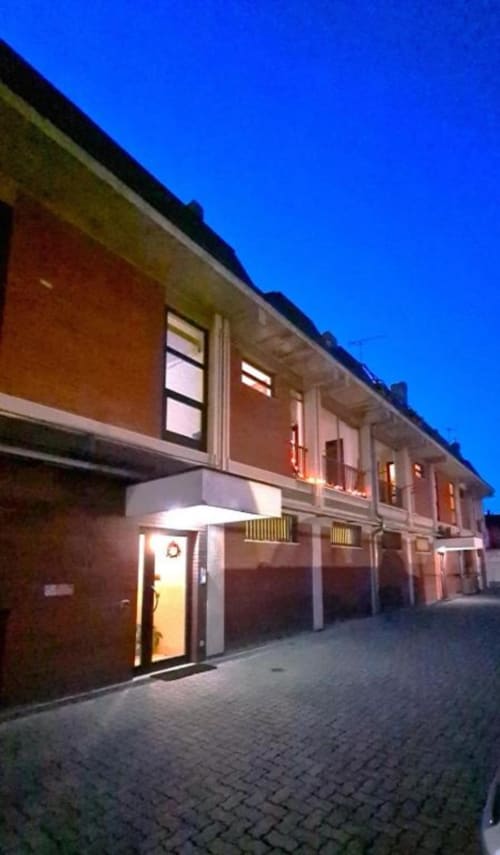 Esterno degli Appartamenti MiSaNi al tramonto, moderno edificio in mattoni con finestre illuminate e ingresso