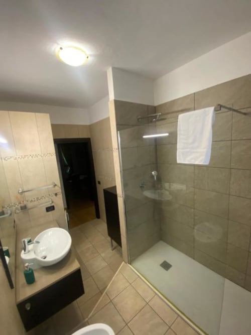 Bagno moderno presso gli Appartamenti MiSaNi con doccia, lavabo, wc e pareti piastrellate in tonalità neutre