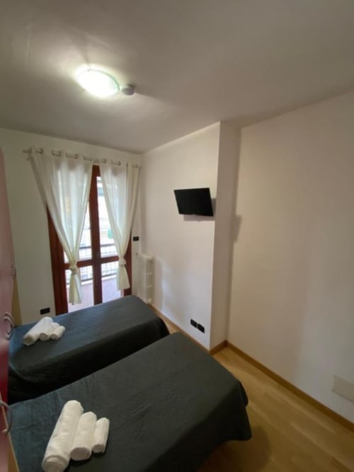 Camera moderna di MiSaNi Apartments con due letti, TV, pavimenti in legno e balcone con tende