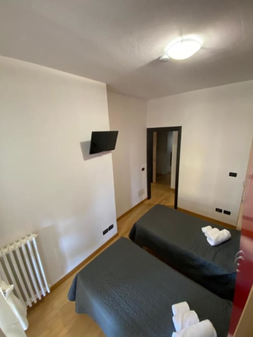 Camera moderna presso MiSaNi Apartments con due letti, TV a parete, riscaldamento radiante e pareti bianche minimaliste