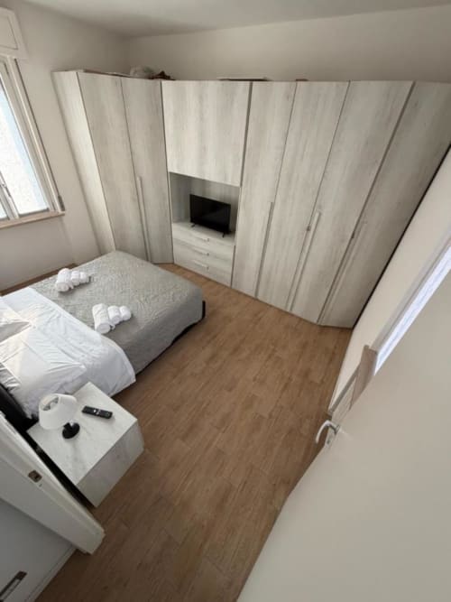 Camera moderna agli MiSaNi Apartments con pavimenti in legno, guardaroba incassato, letto e unità TV