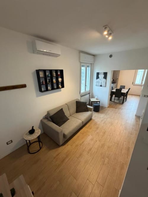Soggiorno moderno MiSaNi Apartments con divano beige, pavimentazione in legno, scaffali a parete e zona pranzo open-plan