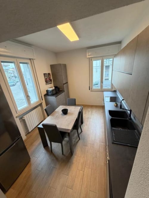Cucina moderna e zona pranzo dell'appartamento con pavimenti in legno, tavolo da pranzo, angolo cottura attrezzato e finestre presso MiSaNi
