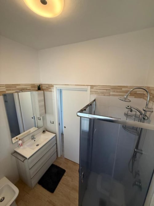 Bagno moderno in MiSaNi Apartments Santa Rita Home con lavabo, specchio, box doccia e pavimentazione in legno