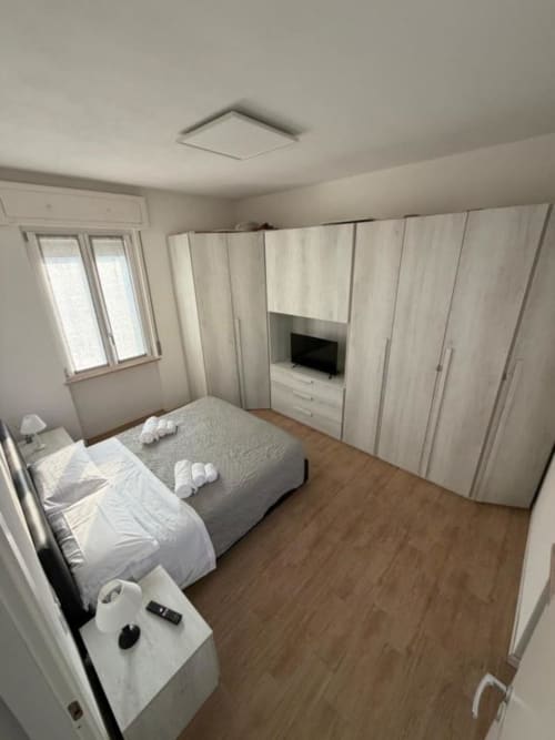 Camera moderna negli MiSaNi Apartments con letto matrimoniale, armadio integrato, mobile TV, pavimentazione in legno e finestra con vista sul giardino
