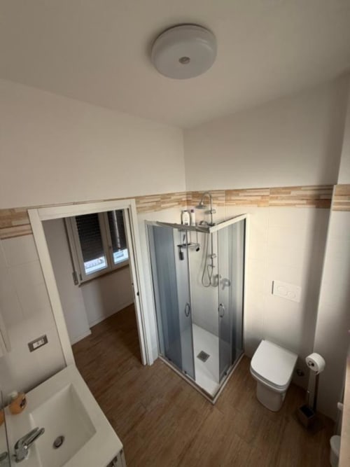 Bagno moderno nell'appartamento Santa Rita Home con cabina doccia, toilette, bidet e pavimentazione effetto legno