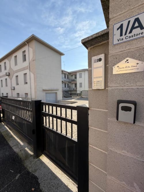 Ingresso degli Apartamenti MiSaNi su Via Castore con cancellata nera e videocitofono, Italia
