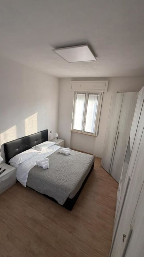 Camera moderna agli MiSaNi Apartments con letto matrimoniale, armadi bianchi, pavimento in legno e finestra con lucernario