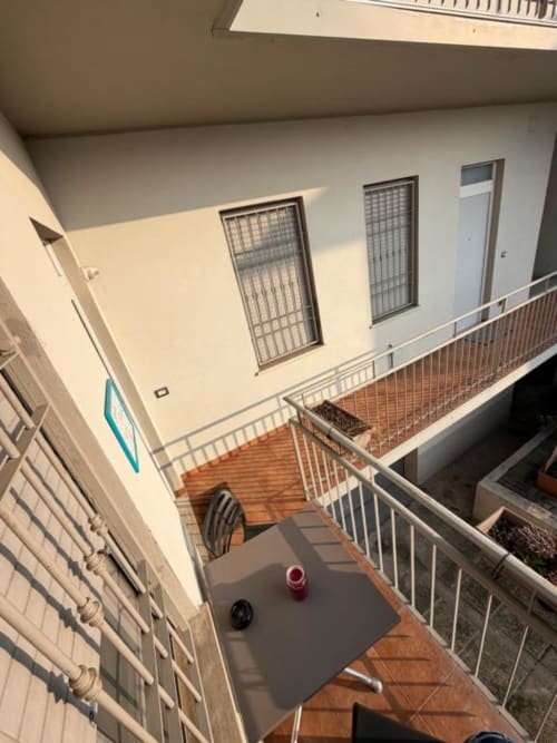 Balcone dell'appartamento Santa Rita con ringhiere bianche, piastrelle in cotto e vista sul giardino - MiSaNi Apartments
