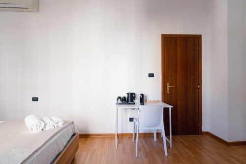 Camera da letto al Centrale Bologna BnB con porta in legno, bollitore/caffettiera, comodino bianco e pavimento in legno