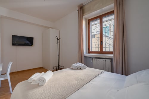 Camera moderna al Centrale Bologna con letto matrimoniale, TV a schermo piatto e vista sulla città dalle finestre in legno intarsiato