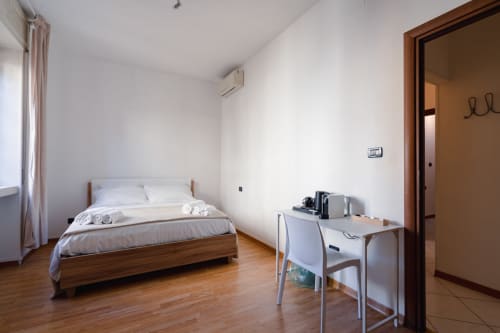 Camera moderna a Centrale Bologna con letto in legno, scrivania e pavimenti in parquet a Bologna, Italia