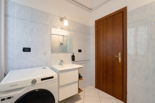 Bagno moderno nella struttura Centrale Bologna con lavatrice, lavandino, specchio e porta in legno a Bologna, Italia