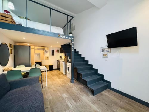 Suíte em estilo loft moderno no Charme da Graça, Lisboa, com mezanino, escadas azuis e TV de tela plana