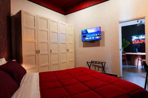 Suite Moderna Urbana presso LH51 Napoli con biancheria rossa, armadi color crema, TV a parete e zona living open-plan
