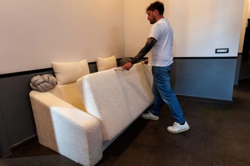 Uomo che sistema la biancheria su un divano color crema presso LH51 Rooms, appartamento a Napoli