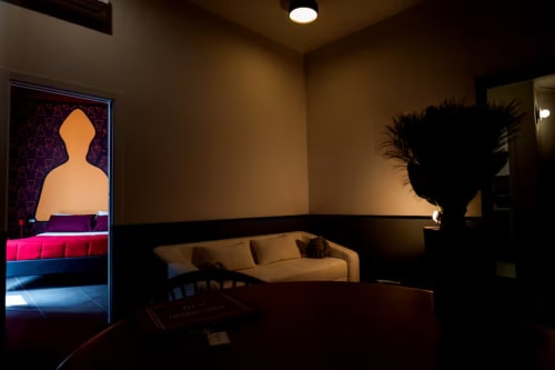 Suite moderna presso LH51 Rooms a Napoli con divano beige, insegna al neon e design dell'illuminazione contemporaneo