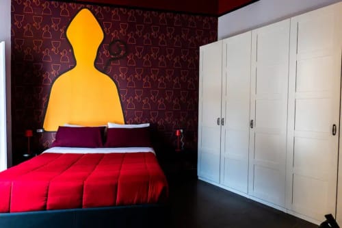 Suite LH51 Napoli moderna con biancheria rossa, testata illuminata in giallo, parete a motivi bordeaux, armadi bianchi