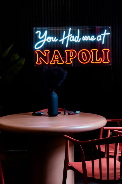 Insegna al neon 'You Had me at NAPOLI' sopra un tavolo rotondo con sedie rosse presso LH51 Rooms and Apartments