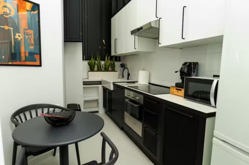 Cucina moderna nell'appartamento LH51 di Napoli con mobili bianco e nero, tavolo da pranzo e elettrodomestici
