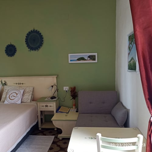 Camera Sarda bedroom at B&B Eleonora D'Arborea in Posada with green walls, bed, sofa, and coastal decor