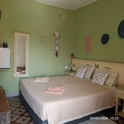 Camera Sarda bedroom at B&B Eleonora D'Arborea in Posada with queen bed, green walls, and traditional Sardinian décor