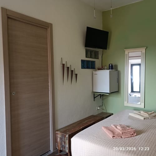 Cozy bedroom in B&B Eleonora D'Arborea, Posada with TV, mini-fridge, and green accent wall