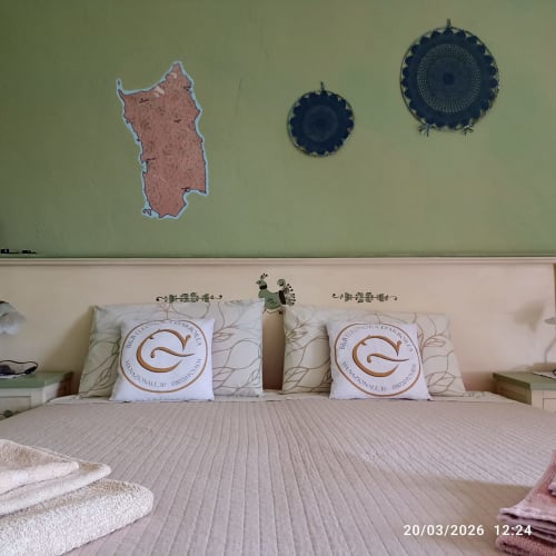 Bedroom at B&B Eleonora D'Arborea in Posada with two beds, decorative pillows, and Sardinian wall art