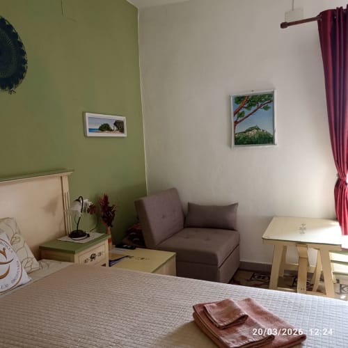Cozy bedroom at B&B Eleonora D'Arborea in Posada with green accent wall, brown sofa, and framed landscape artwork