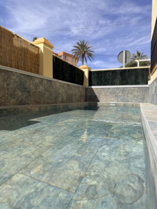Modern pool with clear water at El Chalecito de Alicante hotel, yellow buildings and palm trees in Mediterranean setting