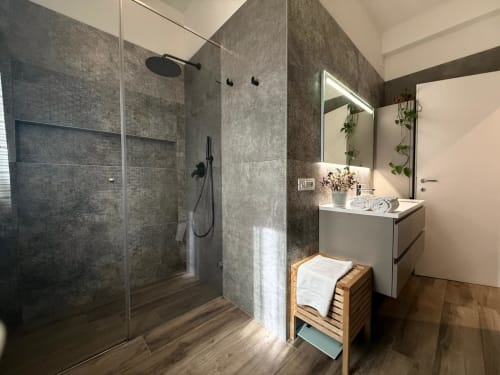 Bagno moderno con doccia a filo pavimento in piastrelle grigie, vanity bianca, mobili in legno e specchio presso l'hotel STAYIN VERONA a Verona