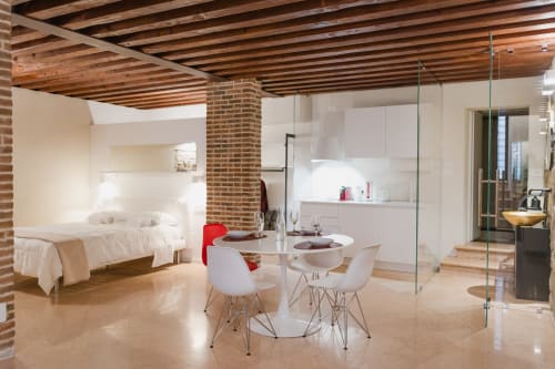 Monolocale moderno a Verona con soffitto in mattoni a vista, arredi bianchi e spazi camera e cucina integrati
