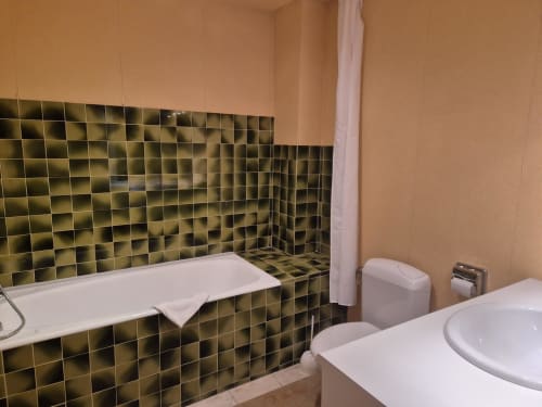 Salle de bain de la Chambre 23 à l'Hôtel Saint Jean, Chalon sur Saône, avec baignoire, toilettes et finitions en carrelage doré