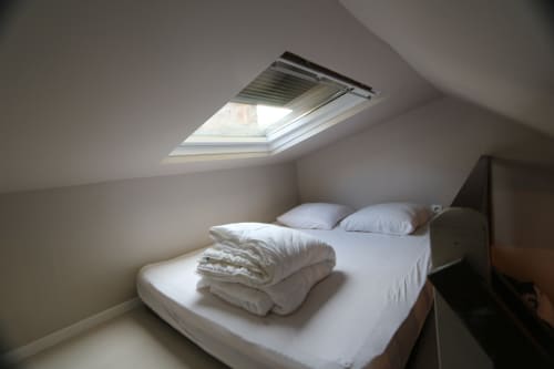 Chambre mezzanine avec puits de lumière, literie blanche et oreillers à l'Appart'Hôtel Résidence de Tourisme de Cholet