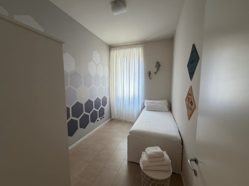 Modern bedroom at DV Garda Suite, Campione, with geometric wall art, single bed, and bright natural light
