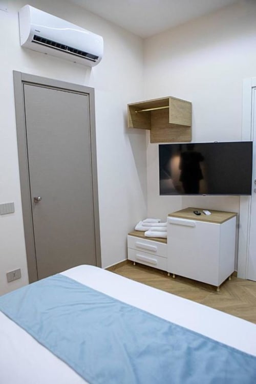 Camera doppia moderna al Dreams & Colors B&B di Napoli con TV a schermo piatto, mobile in legno, climatizzatore split e biancheria blu