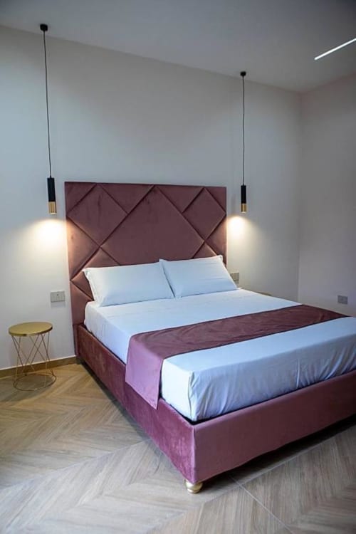 Camera moderna di Dreams & Colors B&B Napoli con testata trapuntata bordeaux, biancheria bianca e lampade a sospensione
