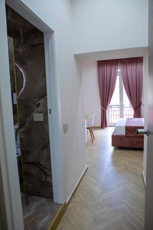 Corridoio della camera tripla Dreams & Colors Naples con bagno, pavimenti in marmo e camera da letto con tende bordeaux
