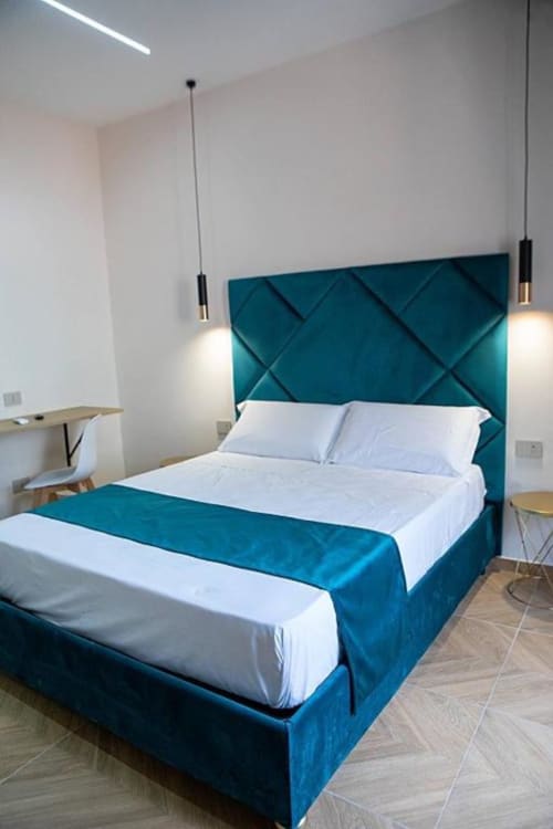 Camera tripla moderna al Dreams & Colors B&B di Napoli con letto rivestito in tela azzurra, biancheria bianca, lampade a sospensione e marmo