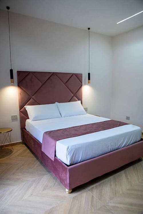 Camera moderna al Dreams & Colors B&B di Napoli con letto imbottito bordeaux, biancheria bianca, illuminazione a sospensione e arredamento in legno