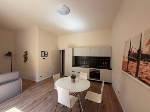 Modern apartment living space at DV Garda Suite Campione with kitchen, dining table, sofa and hardwood floors
