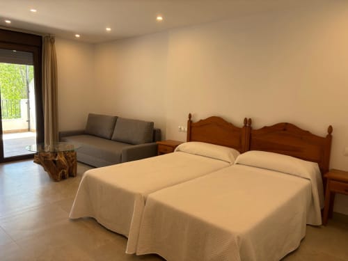 Spacious suite at Hotel Mulhacén Trevélez with twin beds, sofa, and balcony overlooking the river in Granada