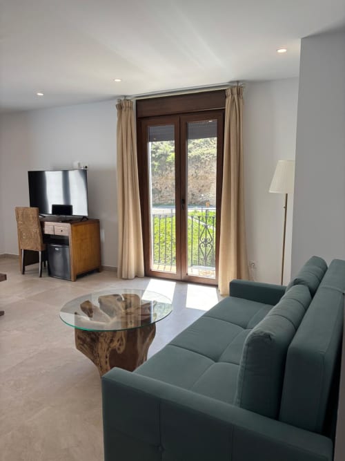Junior Suite at Hotel Mulhacén with green sofa, river view balcony, and modern amenities in Trevélez, Granada