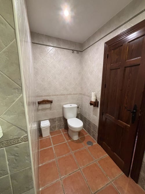 Baño de la Suite Junior Terraza Río en Hotel Mulhacén Trevélez con inodoro, suelo de azulejo terracota y paredes alicatadas en beige