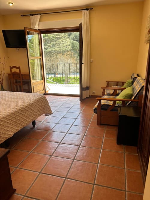 Hotel Mulhacén Trevélez room with terrace, river views, wooden furniture, TV, and balcony overlooking mountains