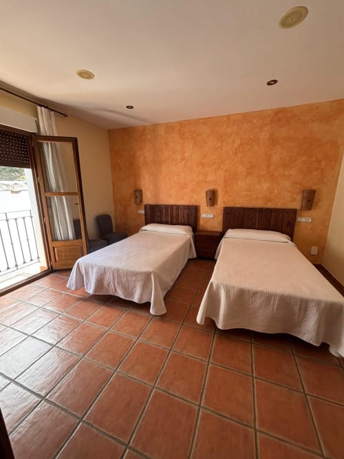 Habitación doble con balcón en Hotel Mulhacén Trevélez, Granada, con azulejos de terracota y paredes ocres