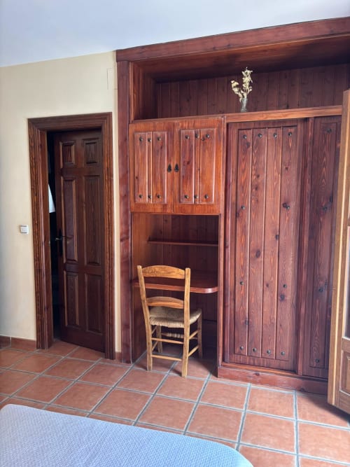 Armarios empotrados de madera y silla rústica en habitación del Hotel Mulhacén Trevélez, Granada