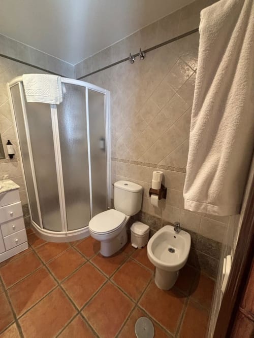 Baño moderno del Hotel Mulhacén Trevélez con mampara de ducha, inodoro, bidé y toallero calefactor