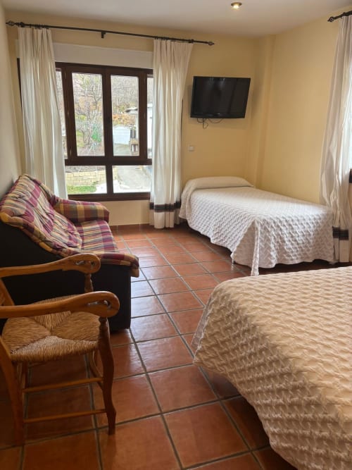 Spacious double room at Hotel Mulhacén Trevélez with two beds, seating area, terracotta tiles, and mountain views through