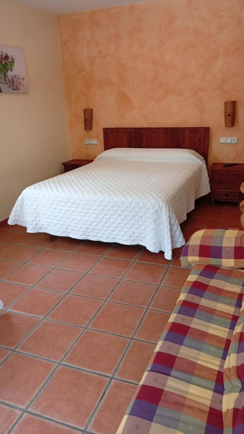 Spacious double bedroom at Hotel Mulhacén Trevélez with white bedding, terracotta tiles, and mountain views in Granada, Spain